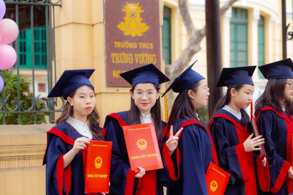 a-group-of-girls-in-graduation-gowns-holding-diplomas-7esagxxsexq